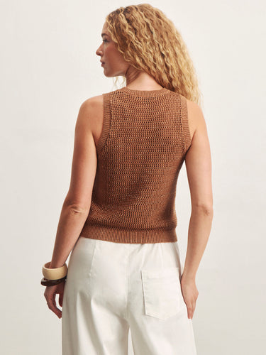 Woman wearing a brown knitted sleeveless top against a plain background