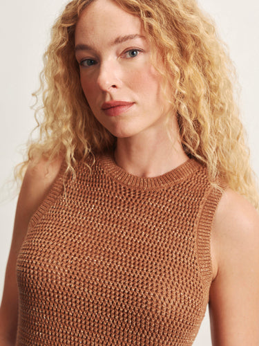 Woman wearing a brown knitted sleeveless top against a plain background
