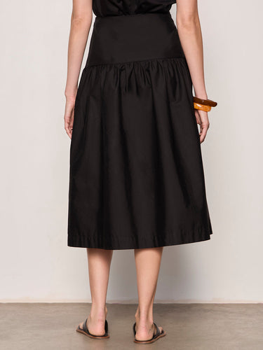 Person wearing a black skirt against a plain background