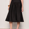 Person wearing a black skirt against a plain background