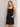 Woman wearing a black sleeveless dress against a plain background