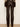 A person shown from the back wearing dark brown faux-leather pants, a brown and beige argyle sweater, and black heels, standing against a plain off-white wall.