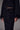 a woman wearing a black sweater with feather cuffs, a mesh midi skirt with a velvet floral pattern and black heels on a grey studio background