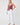 Woman wearing a pink ruffled top and white pants on a white background