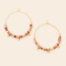 Gold hoop earrings with pink beads on a beige background