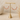 Gold-tone hoop earrings with pink and cream beaded details, displayed on a gold T-stand against a neutral beige background.