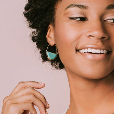 Woman wearing a turquoise earring against a pink background