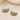 A pair of gold hoop earrings with a polished, semi-circular light green stone inlay, displayed on a soft beige fabric background.