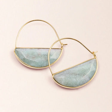Gold hoop earrings with semi-circular jade-like stones on a light pink background