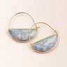 Gold hoop earrings with blue stone half-circle pendants on a light pink background