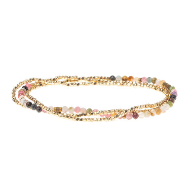 Multicolored beaded bracelet on a gold chain against a white background