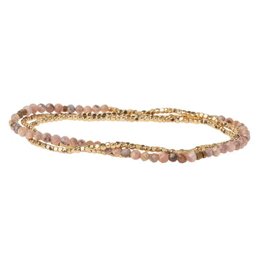 A multi-strand beaded wrap bracelet featuring light pink and beige stone beads accented by gold-tone metallic beads, shown on a plain white background.