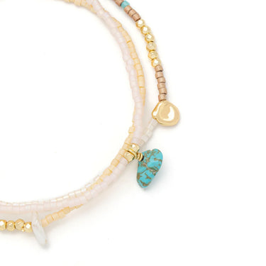 Set of beaded bracelets with gold and turquoise accents on a white background
