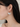 A close-up side profile of a woman wearing a delicate silver hoop earring with a large, semi-circular white stone drop pendant.
