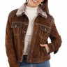 A woman wearing a distressed suede jacket with a faux fur collar and blue jeans on a white background