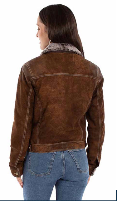 A woman wearing a distressed suede jacket with a faux fur collar and blue jeans on a white background