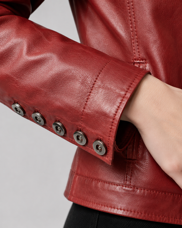 A woman wearing a soft red leather jacket and we see a close up of the sleeve with button detailing