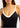 Black one piece swimsuit with white straps worn by a person on a light background