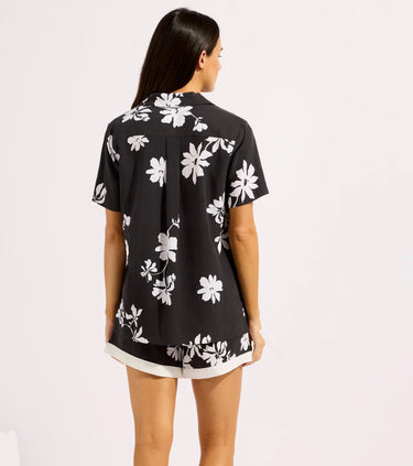 a woman wearing a black floral button up shirt