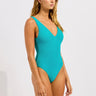 Woman wearing a teal swimsuit against a white background