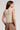 A woman wearing an oat colored crochet floral top and beige pants