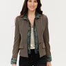 A woman wearing a mixed media jacket that included an inner lining of a denim jacket and the outer layer of a checkered blazer on a white background.