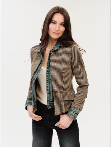 A woman wearing a mixed media jacket that included an inner lining of a denim jacket and the outer layer of a checkered blazer on a white background.