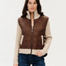 a woman wearing a mixed media jacket that consists of a brown vest and knit sleeves and collar on the jacket.