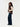 A woman wearing a mixed media knit vest and blue jeans on a white background .