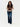 A woman wearing a mixed media knit vest and blue jeans on a white background .