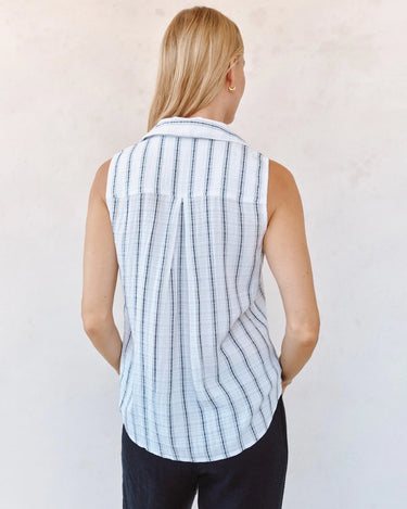 Woman wearing a sleeveless black and white stripe shirt against a plain background