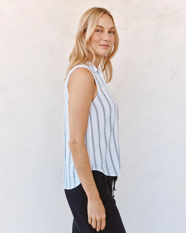 Woman wearing a light black and white striped sleeveless top against a white background