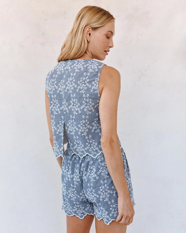Woman wearing a blue floral romper against a white background