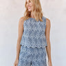 Woman wearing a blue floral sleeveless top and shorts set against a plain background