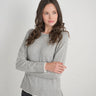 a woman wearing a light grey charcoal sweater with black jeans on a white background