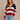 Woman wearing a patriotic striped sweater and jeans against a beige background