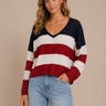 Woman wearing a patriotic striped sweater and jeans against a beige background