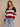 Woman wearing a patriotic striped sweater and jeans against a beige background