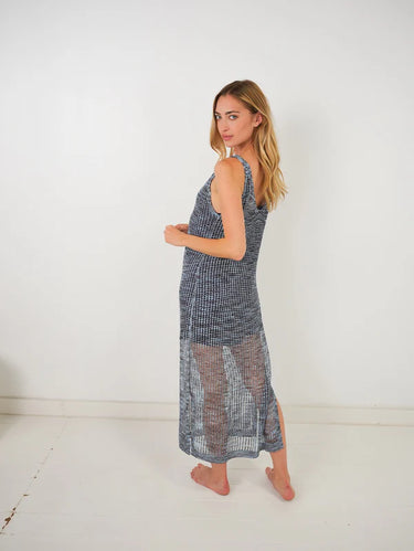 Woman wearing a sleeveless, long dress with a checkered pattern against a white background