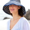 Woman wearing a blue and white striped sun visor with a blurred background