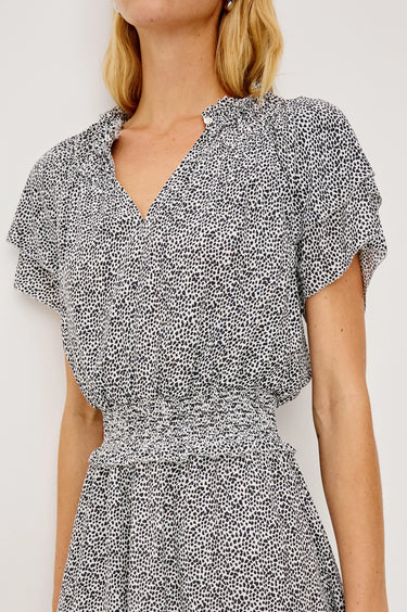 Woman wearing a black and white patterned dress against a plain background