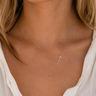 a woman wearing a horizontal gold cross necklace