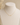 A delicate gold necklace with a minimalist horizontal bar and central cross pendant, displayed on a cream-colored fabric jewelry bust against a soft beige background.