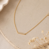 a close up of a CZ bar necklace on a neutral background