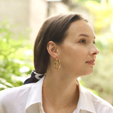 A woman wearing two pairs of hoop earrings