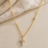 a close up of the pearl cross necklace on a flat surface