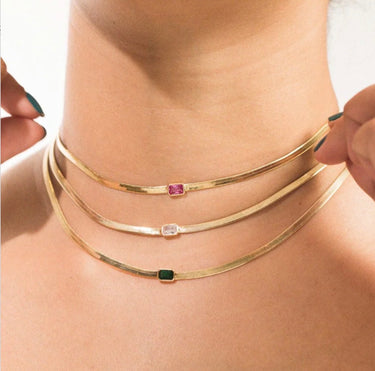 A model wearing three snake chain clicker necklaces with cz gems on the center
