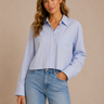 Woman wearing a light blue striped shirt and jeans against a beige background