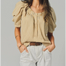 Woman wearing a striped blouse and light pants against a plain background