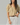 Woman wearing a striped blouse and white pants against a gray background